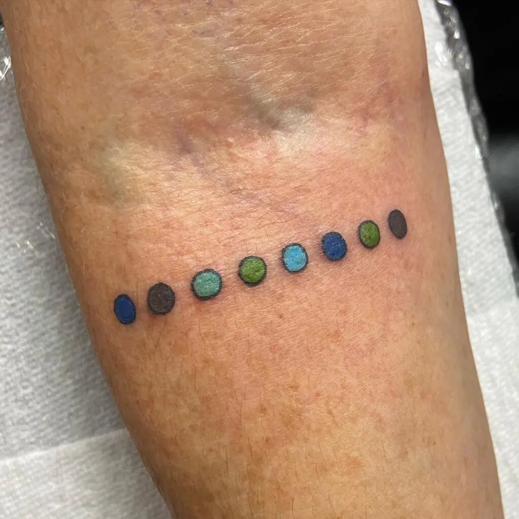 Colorful dots tattoo, representing grandchildren's eye colors with a minimalist design, symbolizing cherished connections and unique individuals
