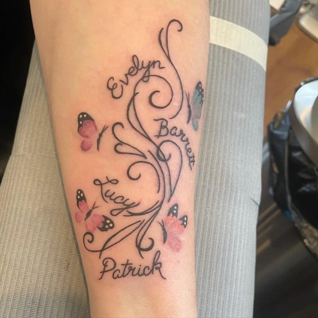 Butterfly and swirls tattoo with grandchildren's names, featuring delicate butterflies in pink and blue, symbolizing transformation and growth