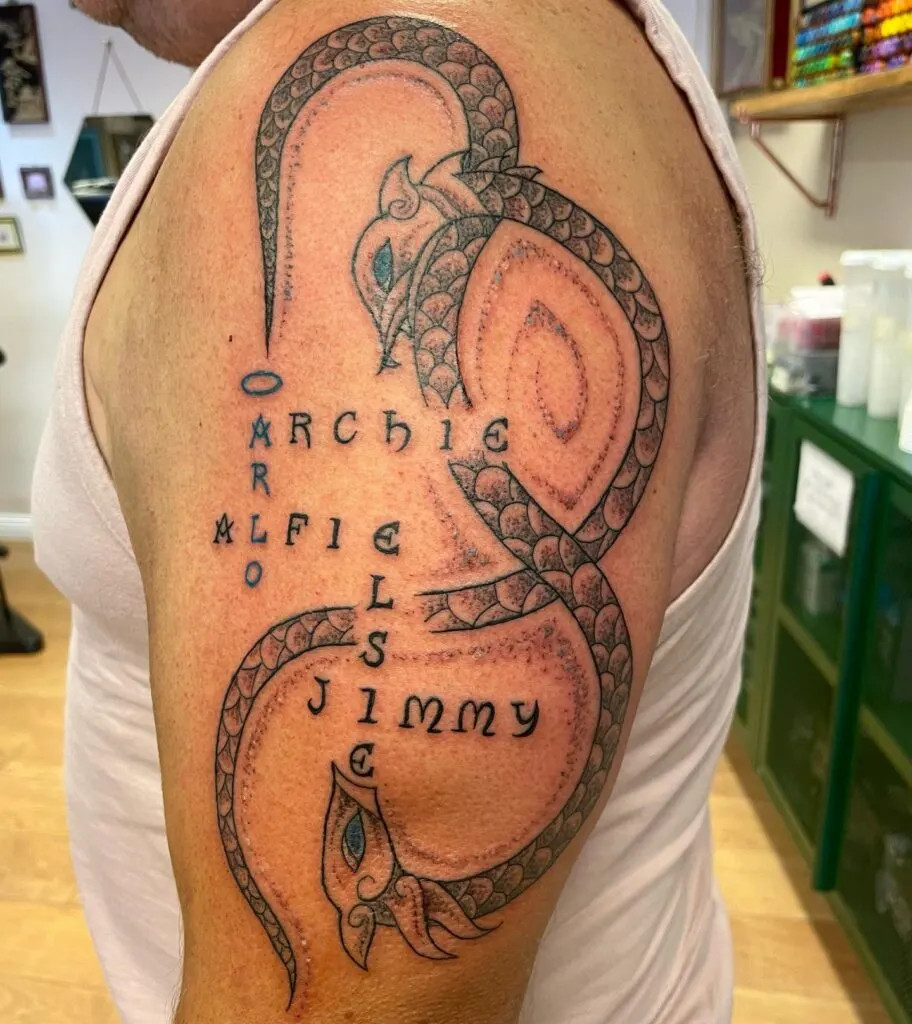 Intricate dragon tattoo with names, symbolizing strength and protection, with each grandchild's name woven into the dragon's body