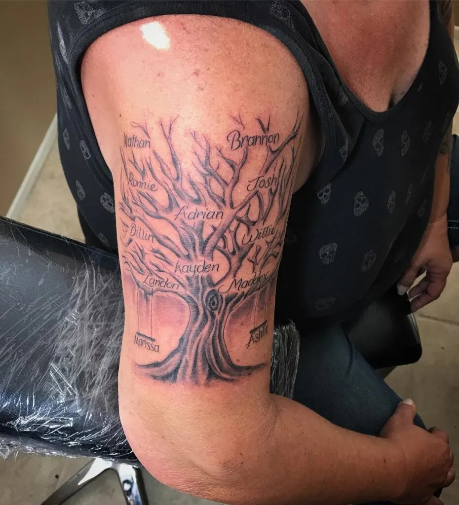 Extended family tree tattoo, symbolizing the family tree with names intricately written among the branches and a swing at the base