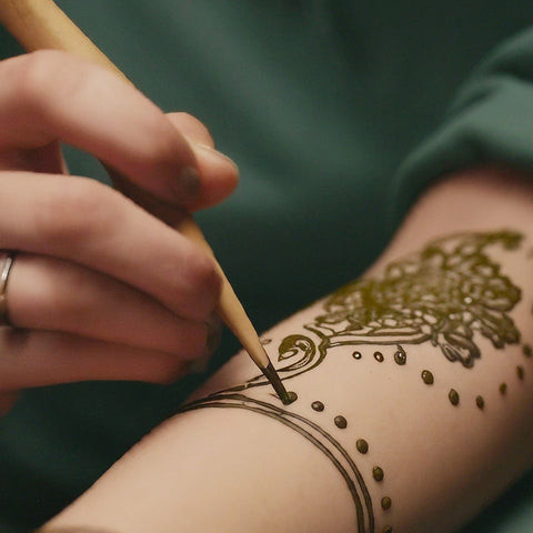A henna artist applying henna paste to a person