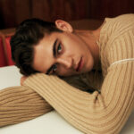 Hero Fiennes Tiffin wearing a knit sweater from Ferragamo, capturing his relaxed yet fashionable style
