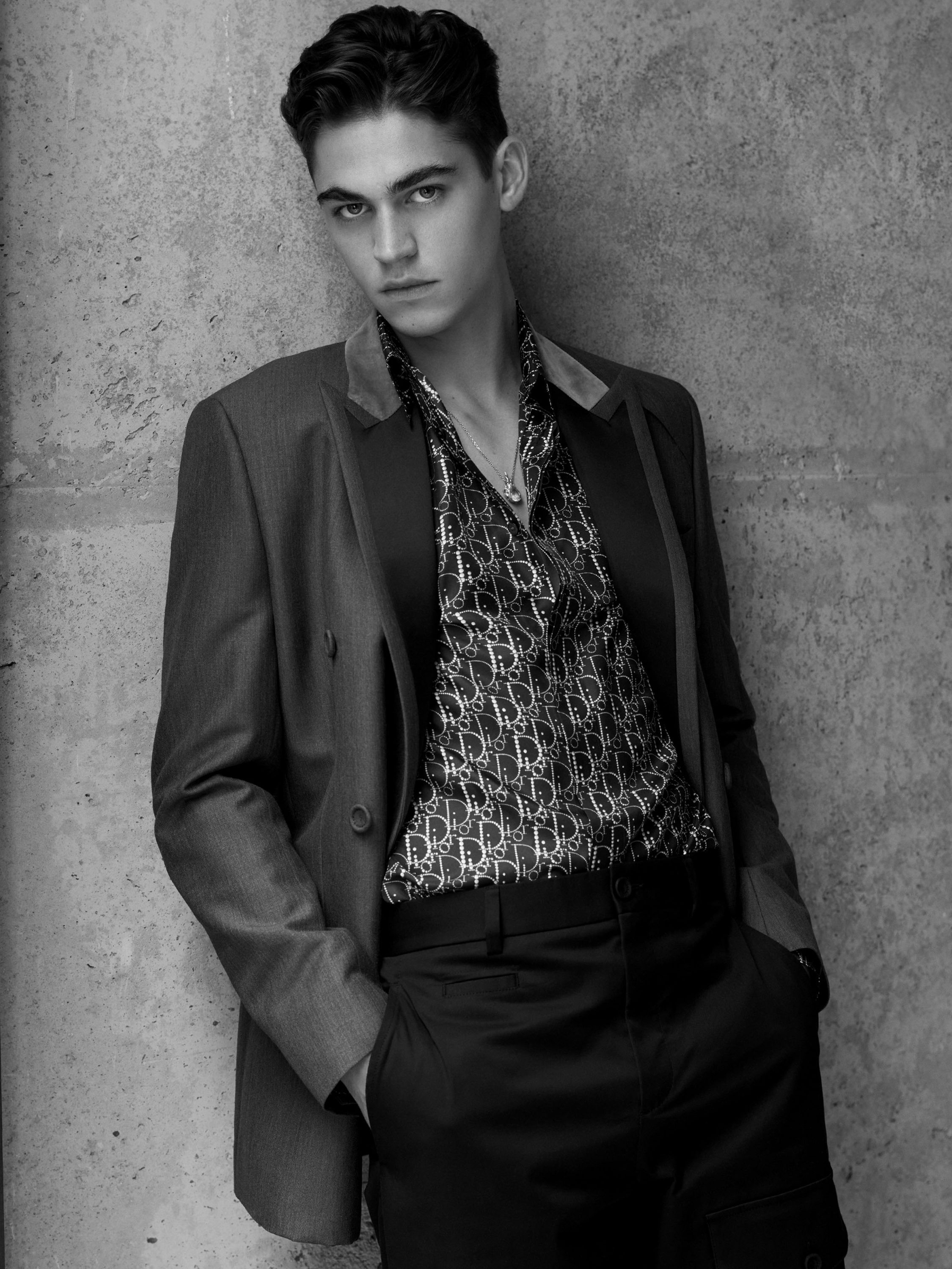 Hero Fiennes Tiffin wearing a suit jacket, silk shirt, and pants from Dior, demonstrating his sophisticated fashion sense