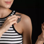 Close-up of a person carefully cleaning a vibrant tattoo with a cotton pad.