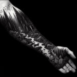 Close-up of a detailed forest sleeve tattoo featuring various tree types and subtle shading