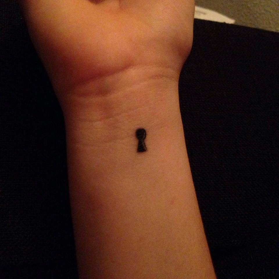 Tiny keyhole wrist tattoo symbolizing mystery