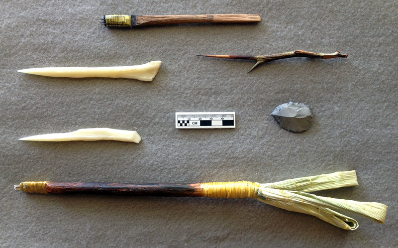 Some examples of tested tools, including deer bone slivers set in a wood handle (top), split deer bone needles (left), honey locust spine, and a stone graver. The tool at the bottom includes steel needles and corn husk rattles, and is based on historic examples from the Great Plains.