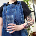 Close-up of a woman drinking water from a clear bottle, emphasizing the importance of hydration for skin health and overall well-being before getting a tattoo