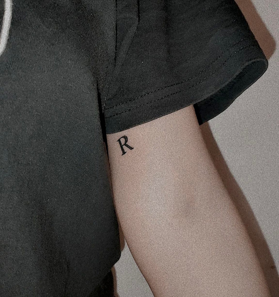 Initial tattoo with black ink