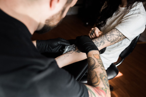 Person carefully cleaning a new tattoo with antibacterial soap and water.