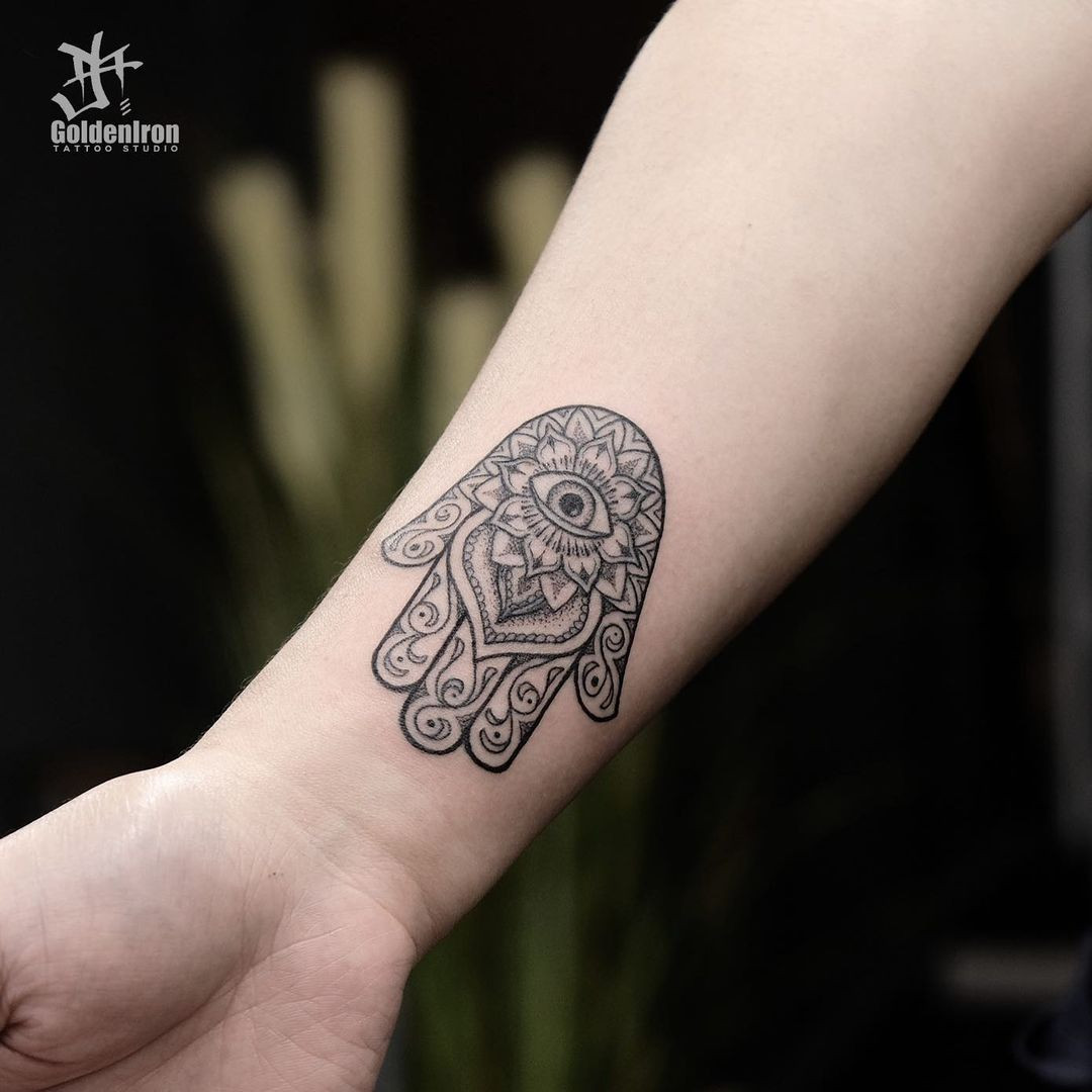 A Hamsa hand tattoo on a woman's hand, believed to ward off evil and provide luck and good fortune.
