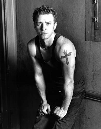 Justin Timberlake's cross tattoo on his left arm, symbolizing his religious beliefs and upbringing in the Bible Belt.