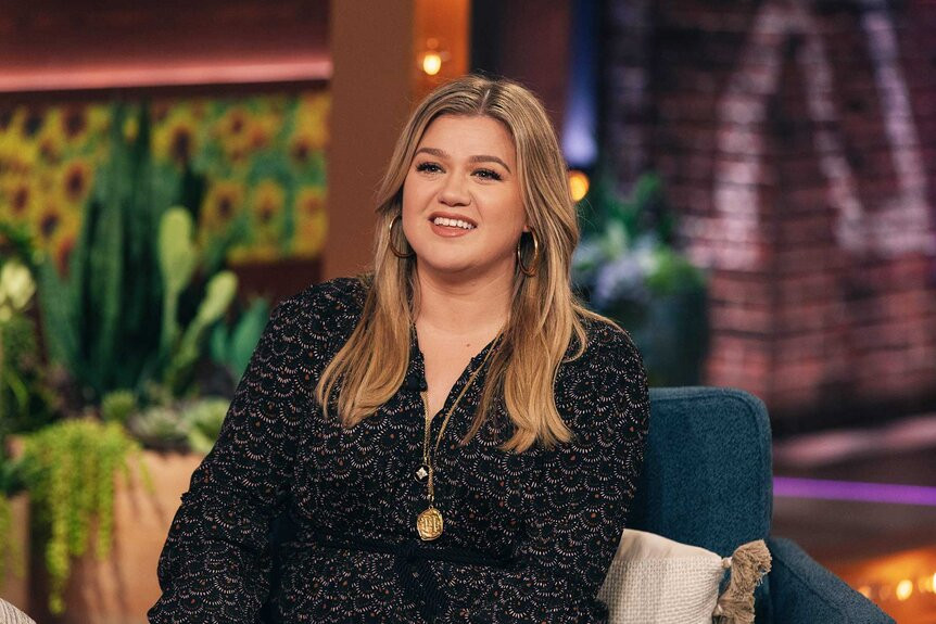 Kelly Clarkson smiling on her talk show, showcasing her vibrant personality and possible tattoo placements