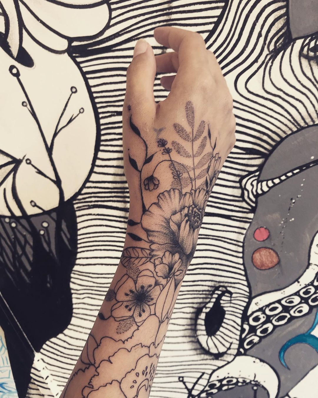 An elaborate floral tattoo on a woman's hand, showcasing a stunning and intricate design.