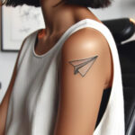 A woman's arm features a paper airplane tattoo, symbolizing her dreams and aspirations.