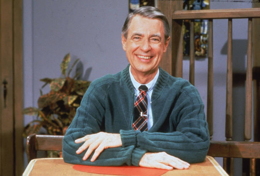 Mr. Rogers in his signature sweater, dispelling the tattoo myth with his gentle demeanor.