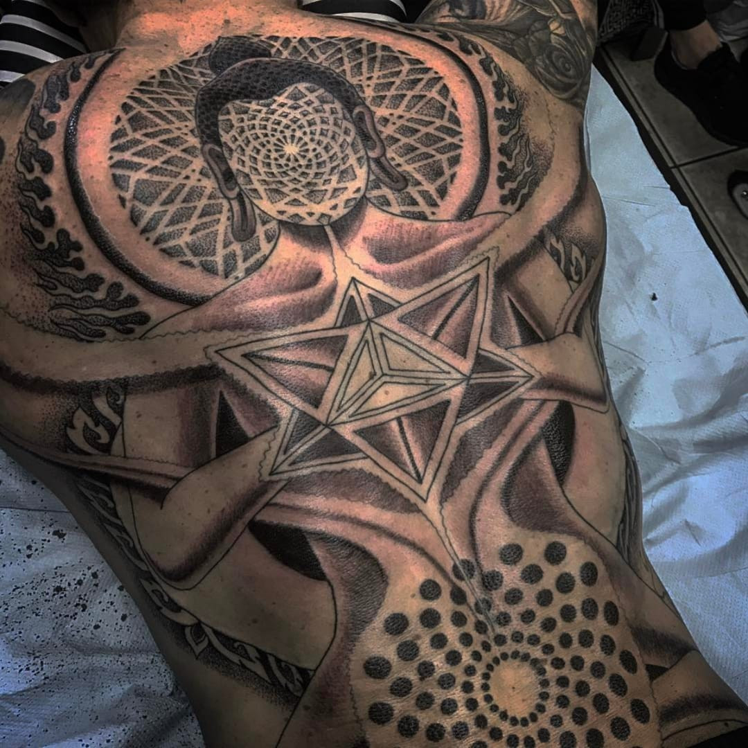 A black and grey Buddha tattoo on a back with sacred geometry
