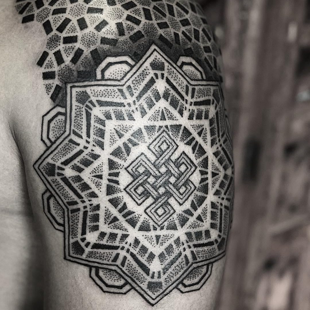 A detailed back tattoo featuring an eternal knot mandala