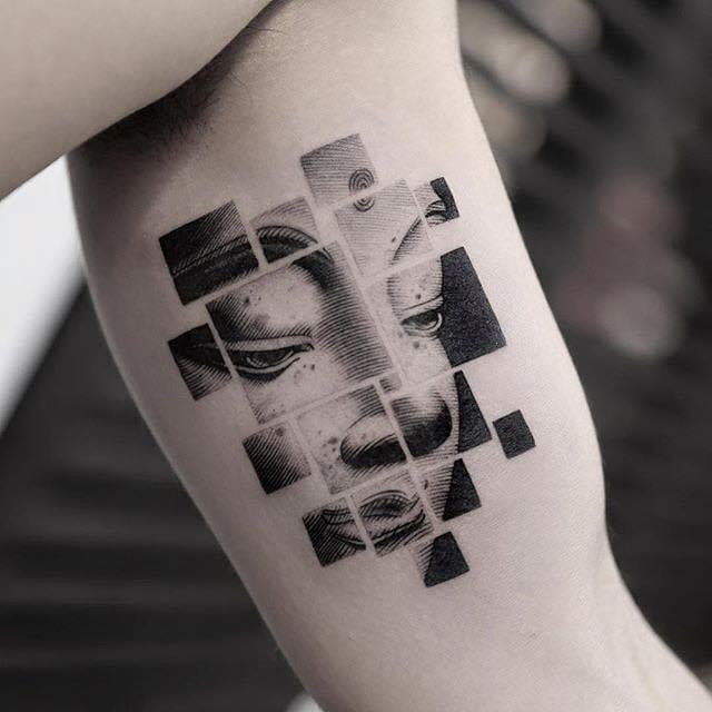 A black and grey Buddha tattoo on an arm
