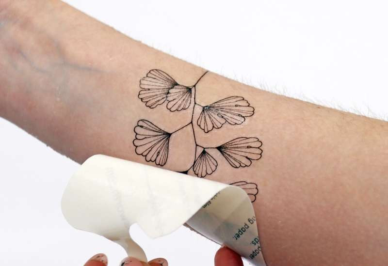 Close-up of peeling off the backing paper from a temporary tattoo, revealing the design