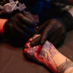 Close-up of a person's arm with a black ink tattoo, showcasing the intricate linework and design