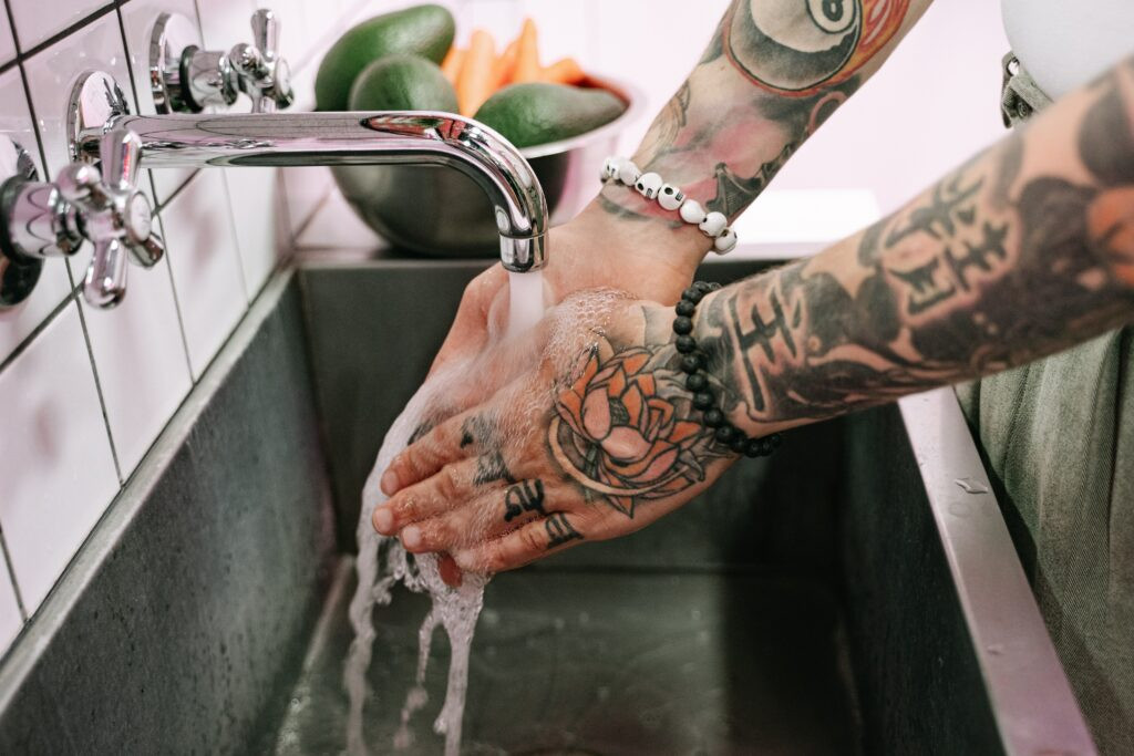 Close up of hands gently washing a new tattoo with antibacterial soap.