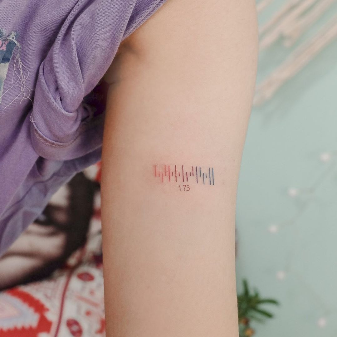 A faded barcode tattoo on a person's arm