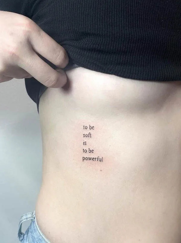 Quote tattoo on the side encouraging vulnerability and self-acceptance.