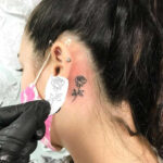 Rose tattoo with delicate linework behind ear