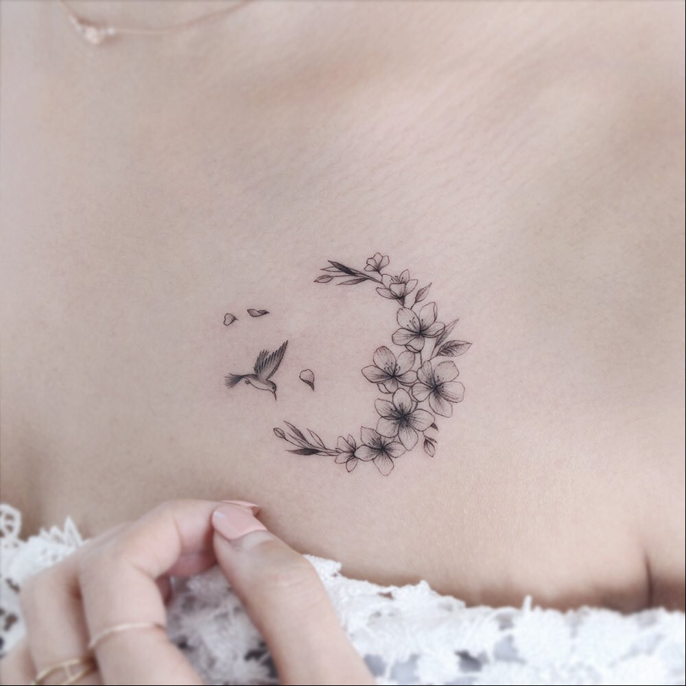 A minimalist design showing a Japanese cherry blossom branch with a few blossoms tattooed on the inner arm.