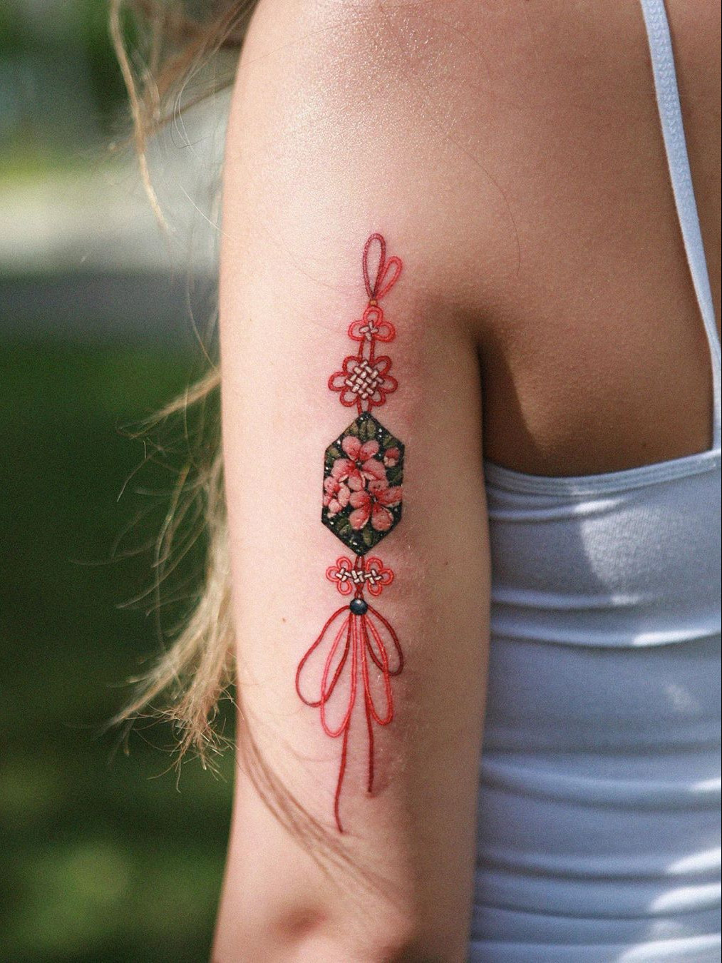A striking forearm tattoo combining Japanese cherry blossoms with flowing geometric patterns.