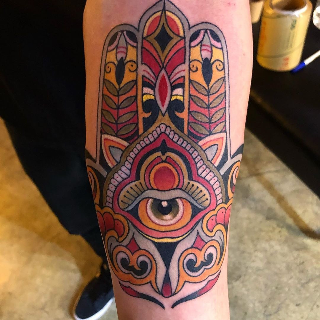 An upward-facing Hamsa tattoo featuring an eye, symbolizing protection against evil and negativity