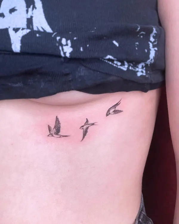 Simple birds underboob tattoo symbolizing freedom and dreams.
