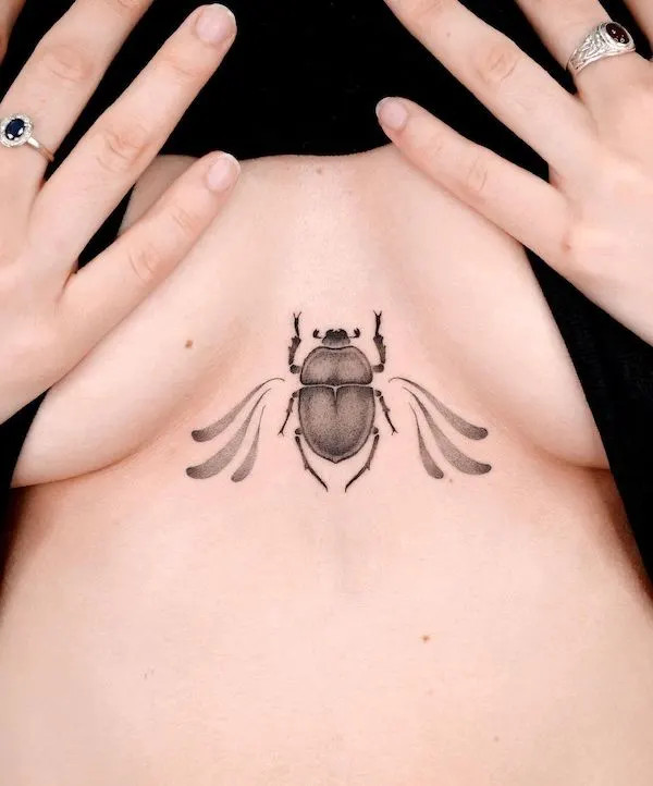 Small beetle underboob tattoo symbolizing protection.