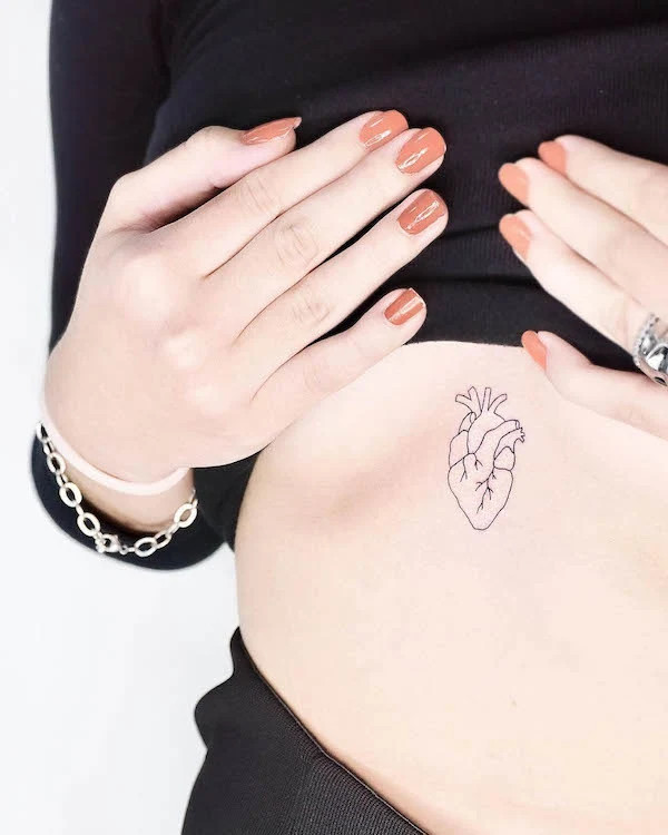Small heart underboob tattoo symbolizing life, love, and inner intuition.