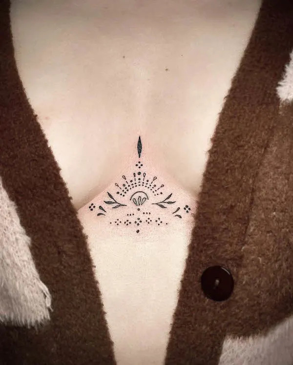 Small ornamental underboob tattoo blending geometric and organic shapes.