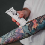 Applying lotion on arm with tattoo