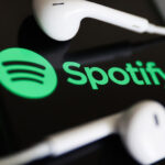 Spotify logo displayed on a phone screen and headphones