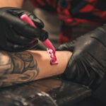 Tattoo artist carefully shaving an arm before a tattoo session