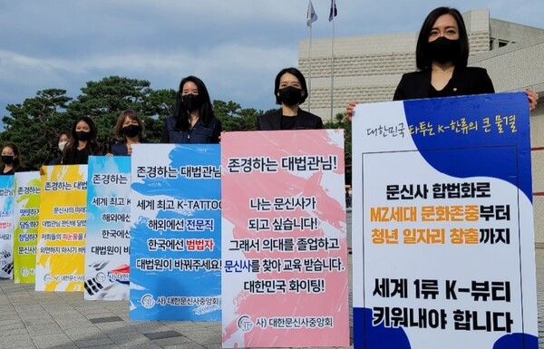 Tattoo artists protesting controversial restrictions in front of the Supreme Court with alt text Korean tattoo artists advocating for tattoo legalization, protesting restrictions on non-medically licensed practitioners