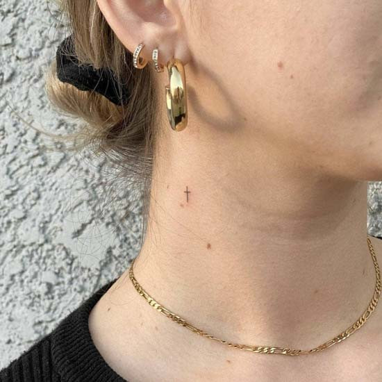 Tiny cross tattoo on woman neck
