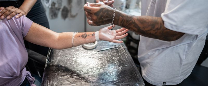 Tattoo artist applying second skin film to client, ensuring a clean and protected healing process