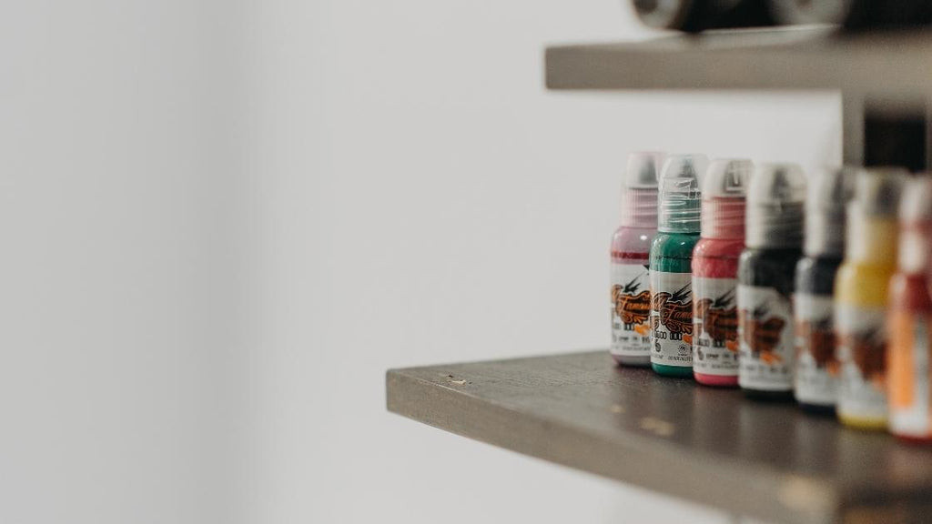 A few different tattoo ink types on a shelf.