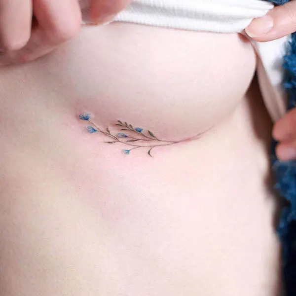 Tiny underboob flower tattoo showcasing minimalist floral elegance.