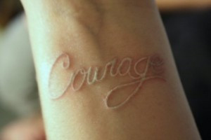 White ink tattoo with intricate floral design on the upper back, demonstrating subtle and elegant body art
