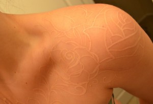 Detailed white ink mandala tattoo on the upper arm, exhibiting intricate patterns and sophisticated artistry