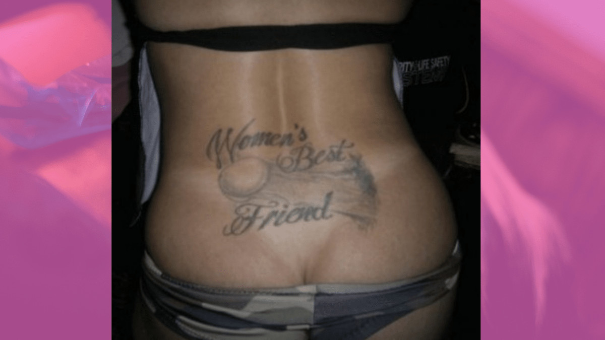 Woman's lower back tattoo with a huge throbbing cock encompassed by the words Woman's best friend