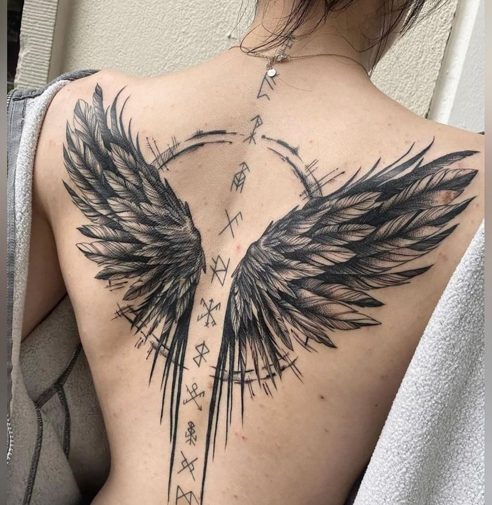 Detailed realistic angel wing tattoo on a woman's back, symbolizing protection and guidance