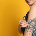Woman applying Aveeno lotion to her floral tattoo on the back of her upper arm