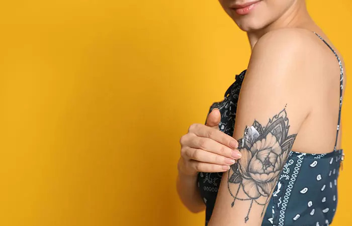 Woman applying Aveeno lotion to her floral tattoo on the back of her upper arm